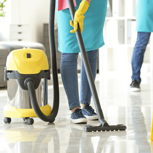 A person using a vacuum cleaner on a glossy floor, wearing gloves and a colorful uniform.